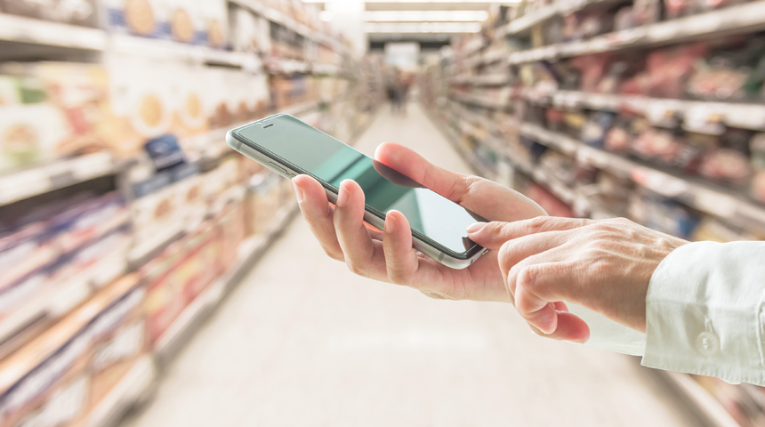 Shopper using mobile smart phone for retail shopping in supermarket