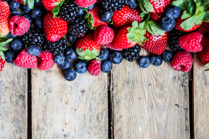 Mix of berries on rustic wooden background